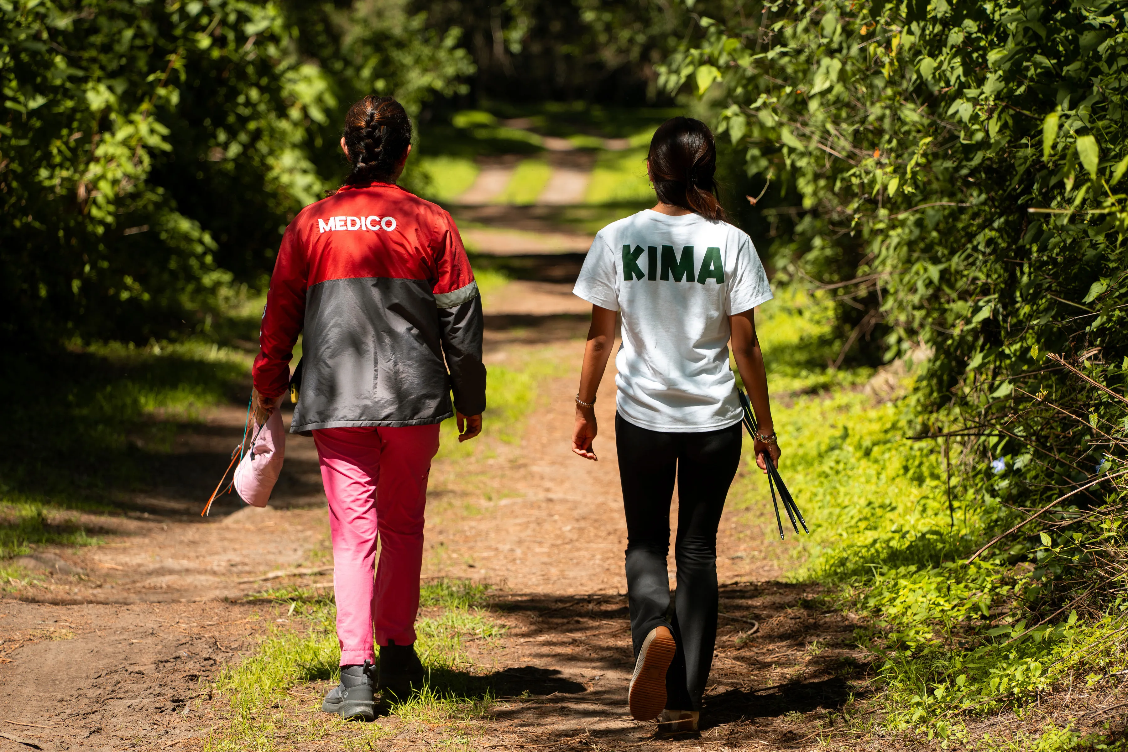 Dos personas del equipo caminan por un sendero entre árboles