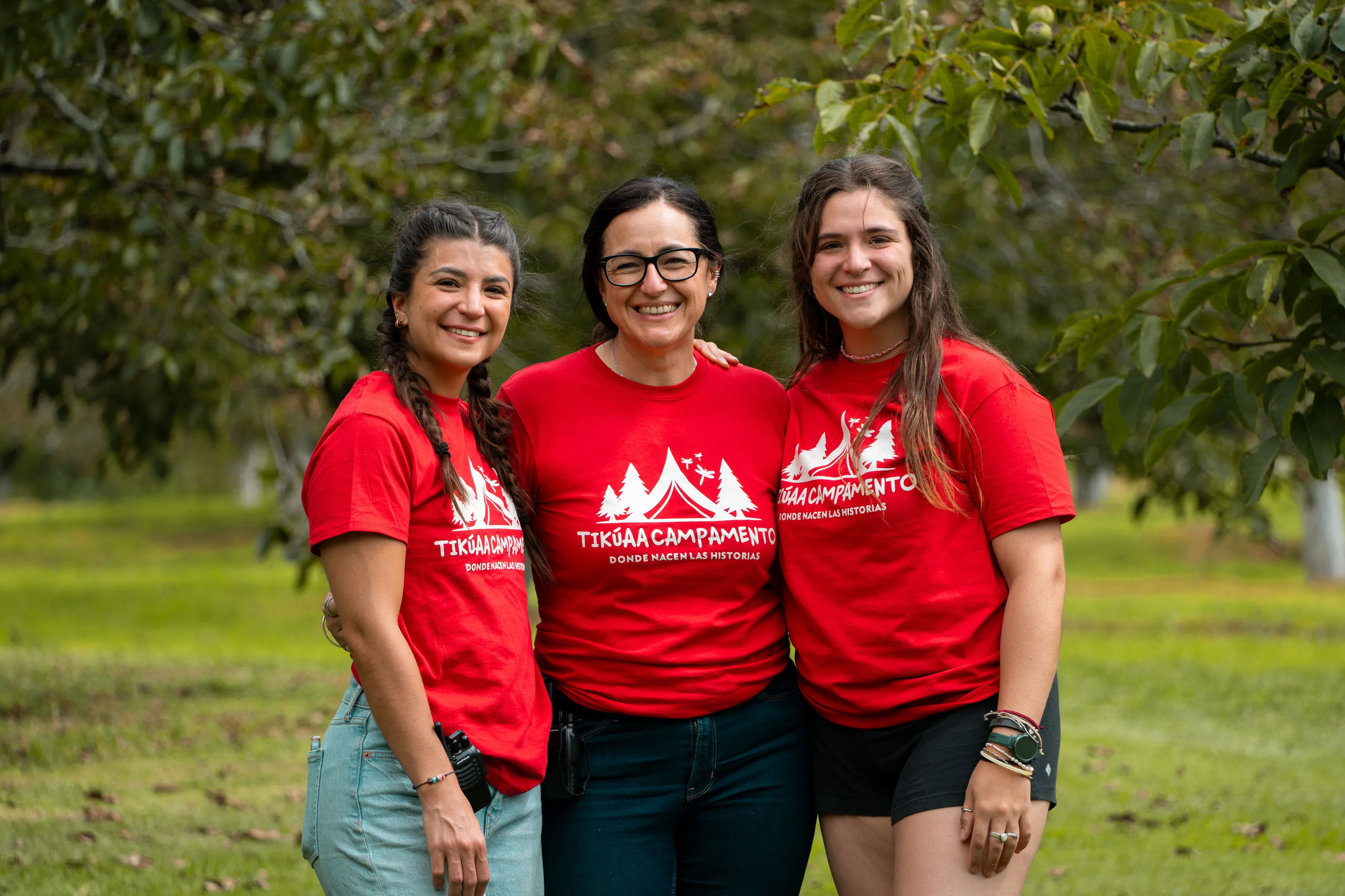 Tres guías de Tikúaa sonriendo con la playera roja del campamento